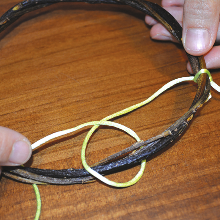 1. Завяжите атласный шнур вокруг деревянного обруча и, отступив немного, сделайте виток.