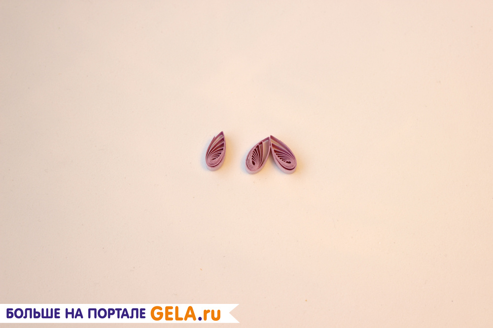 Для верхних лепестков из ½ полоски фиолетового цвета скрутите два модуля «капля». Склейте основаниями между собой.
